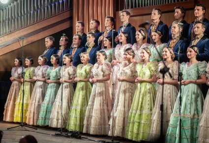 Na scenie Artyści chóru w stylowych kostiumach z końca XIX w. w rzędach