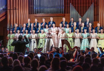 Na scenie Artyści chóru w stylowych kostiumach z końca XIX w. a przed nimi maestro Jacek Boniecki i część publiczności
