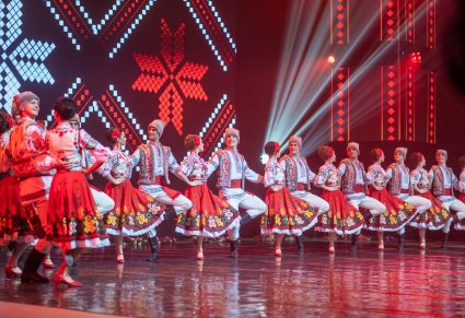 Na scenie Artyści z zespołu Baletul Național JOC w kostiumach ludowych w trakcie wykonywania choreografii tanecznej