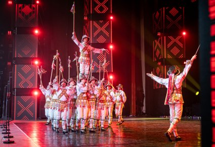 Artyści z zespołu Baletul Național JOC w kostiumach ludowych podczas wykonywania choreografii tanecznej na scenie