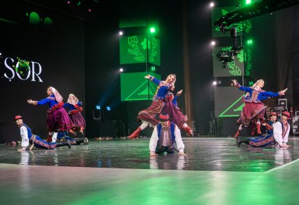 Pary Artystów w kostiumach podegrodzkich z zespołu "Mazowsze" w trakcie wykonywania choreografii tanecznej na scenie