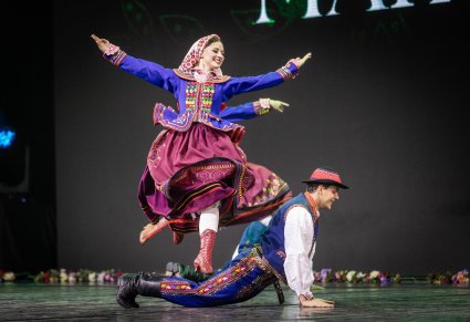 Para Artystów w kostiumach podegrodzkich z zespołu "Mazowsze" w trakcie wykonywania choreografii tanecznej a scenie