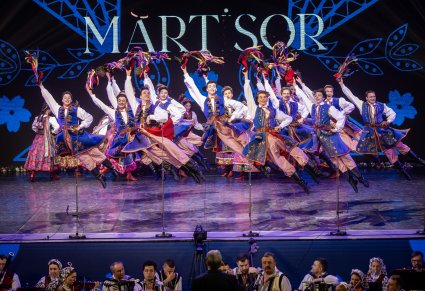 Artyści zespołu "Mazowsze" w kostiumach krakowskich w trakcie wykonywania choreografii tanecznej na scenie