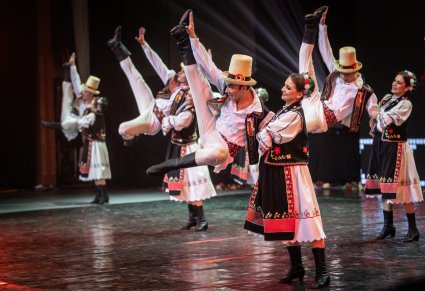 Pary Artystów z zespołu Baletul Național JOC w kostiumach ludowych w trakcie wykonywania choreografii tanecznej na scenie