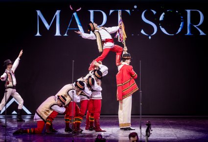 Artyści z zespołu Baletul Național JOC w kostiumach ludowych w trakcie wykonywania figury tanecznej na scenie