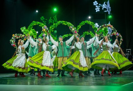 Zbliżenie na Artystów z zespołu "Mazowsze" w kostiumach lubuskich w trakcie wykonywania choreografii tanecznej na scenie