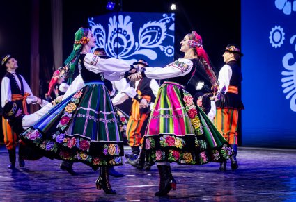 Zbliżenie na dwie Artystki z zespołu "Mazowsze" w kostiumach łowickich w trakcie wykonywania figury tanecznej