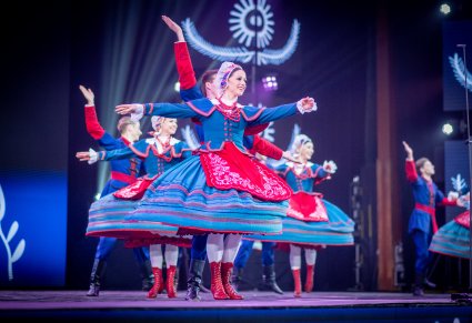 Pary Artystów z zespołu "Mazowsze" w kostiumach kujawskich na scenie podczas wykonywania choreografii tanecznej
