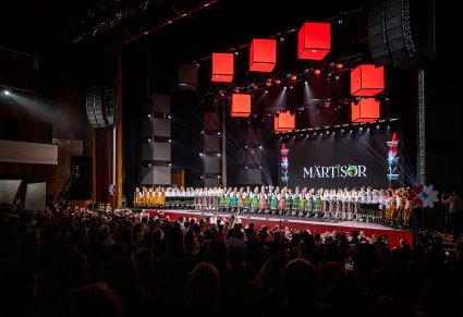 Na scenie Artyści zespołu "Mazowsze" wraz z Artystami zespołu Baletul Național JOC  w kostiumach ludowych, widoczna publiczność