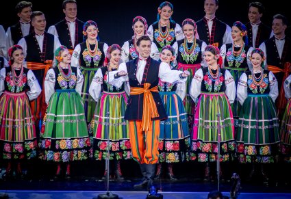 Zbliżenie na Artystów zespołu "Mazowsze" z chóru w kostiumach łowickich wykonujących z Solistą utwór "Furman"