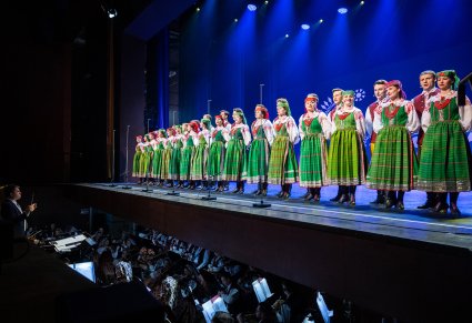 Artyści chóru z zespołu "Mazowsze" w kostiumach kurpiowskich na scenie