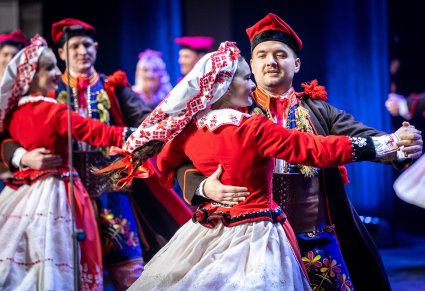 Zbliżenie na pary Artystów w kostiumach ludowych wykonujących choreografię taneczną na scenie