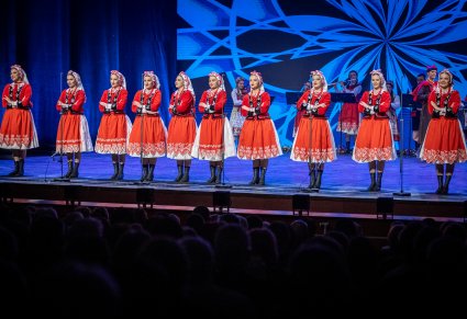 Artystki w kostiumach ludowych ustawione w rzędzie na scenie