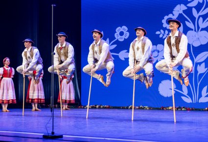 Pięciu Artystów w kostiumach jurgowskich z zespołu "Mazowsze" w trakcie wykonywania akrobacji tanecznych na scenie