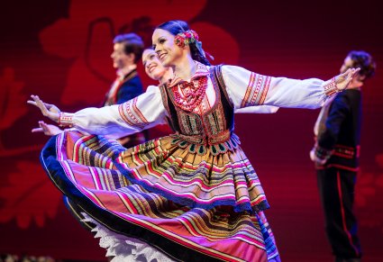 Zbliżenie na Artystkę z zespołu "Mazowsze" w kostiumie krzczonowskim podczas wykonywania choreografii tanecznej na scenie