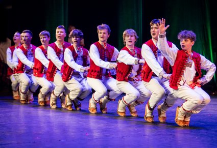 Tancerze w kostiumach ludowych podczas wykonywania choreografii tanecznej na scenie