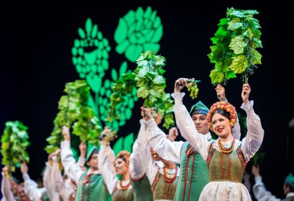 Zbliżenie na Artystów z zespołu "Mazowsze" w kostiumach lubuskich podczas wykonywania choreografii tanecznej na scenie