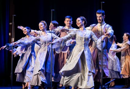 Tancerze w kostiumach ludowych w trakcie wykonywania choreografii tanecznej na scenie