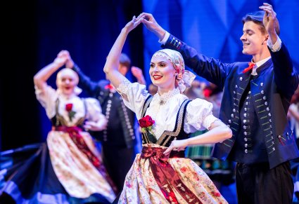 Zbliżenie na uśmiechniętą parę tancerzy w kostiumach ludowych w trakcie wykonywania choreografii tanecznej