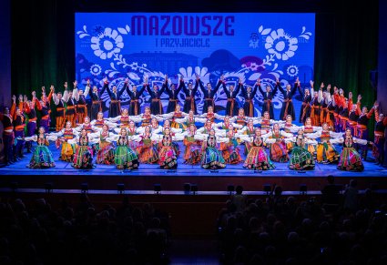 Artyści z zespołu "Mazowsze" w kostiumach ludowych podczas wykonywania finałowej choreografii tanecznej
