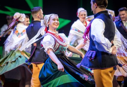 Zbliżenie na tancerzy w kostiumach ludowych podczas wykonywania choreografii tanecznej na scenie