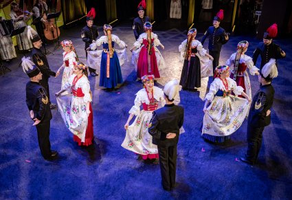 Tancerze w kostiumach ludowych podczas wykonywania choreografii tanecznej na scenie