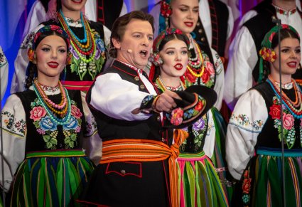 Zbliżenie na solistę chóru podczas koncertu z widocznych chórem w tle