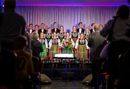 Zbliżenie na chór w kostiumach łowickich podczas występu, po bokach widoczna widownia