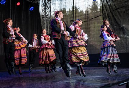 Grupa tancerzy w kostiumach kszczonowskich na scenie