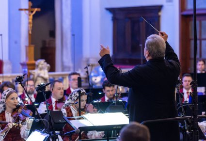 Zbliżenie na Dyrektora Jacka Bonieckiego który jest zwrócony w stronę Orkiestry i dyryguje koncert