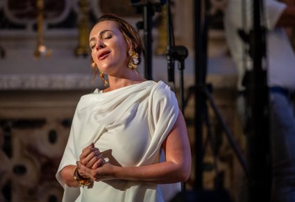 Zbliżenie na śpiewającą solistę w białej, długiej sukience