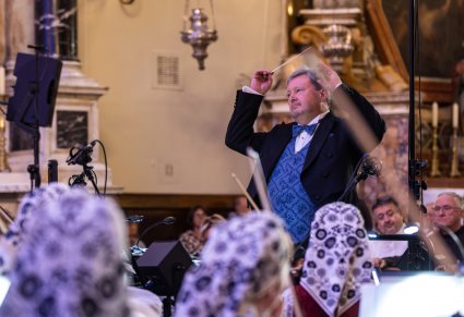 Na pierwszym planie Dyrektor Jacek Boniecki dyrygujący koncert, przed nim część orkiestry