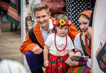 Uśmiechnięta dwójka Artystów w kostiumach sannickich z małą dziewczynką