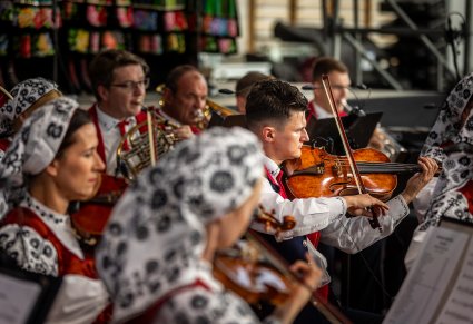 Zbliżenie na artystów orkiestry grających na skrzypcach