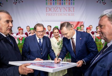 Prezydent podpisujący dożynkowy plakat pamiątkowy