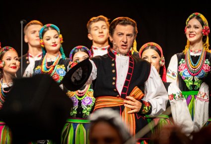 Zbliżenie na solistę chóru podczas koncertu z widocznych chórem w tle