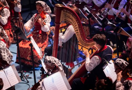 Zbliżenie na artystkę orkiestry grającego na harfie