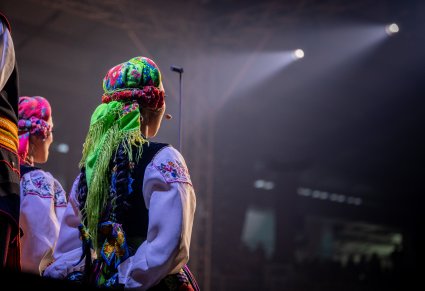 Zbliżenie na artystkę chóru, w tle widoczna sala