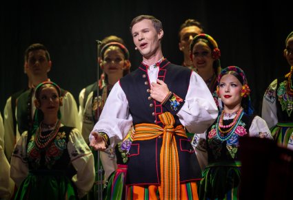 Zbliżenie na solistę chóru podczas koncertu z widocznych chórem w tle