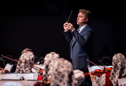 Zbliżenie na dyrygenta i orkiestrę podczas koncertu