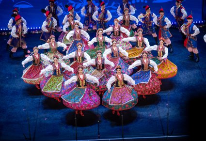 Grupa Artystów w kostiumach krakowskich podczas wykonywania choreografii tanecznej na scenie