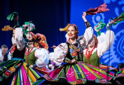 Zbliżenie na Artystkę w kostiumie łowickim, która macha chustą wykonując choreografię taneczną