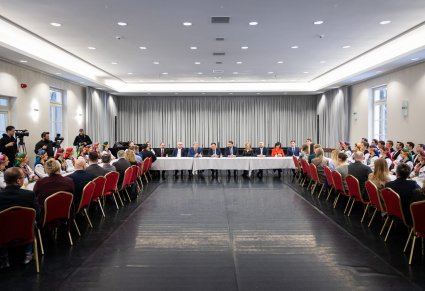 Szerokie ujęcie na wszystkich zgromadzonych przy wspólnym stole podczas rozmów przy kawie