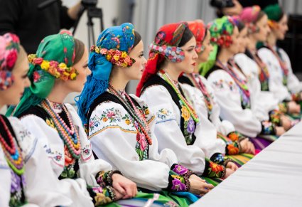 Artystki zespołu Mazowsze w kostiumach łowickich siedzę przy stole