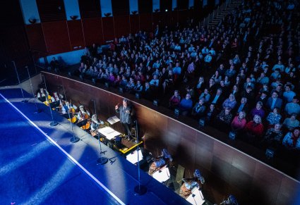 Widok z góry  na dyrygenta, orkiestron oraz widownię