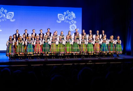 Artyści chóru Mazowsza w kostiumach łowickich śpiewają na scenie