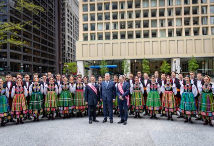 Na pierwszym planie Dyrektor zespołu wraz z Urzędnikami z Chicago, w tle Artyści Chóru w kostiumach łowickich