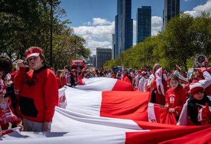 Uczestnicy Parady Konstytucji 3 Maja trzymający dużą flagę Polski