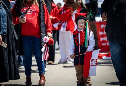 Zbliżenie na małego chłopca w kostiumie krakowskim, trzymającego w ręku flagę Polski na Paradzie Konstytucji 3 Maja w Chicago