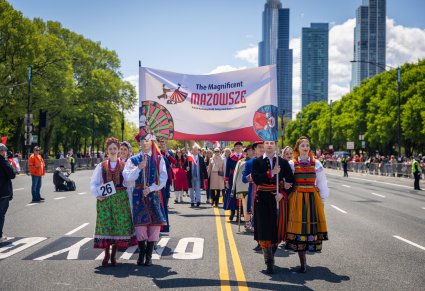Artyści w kostiumach ludowych trzymający baner z logo zespołu "Mazowsze" na Paradzie Konstytucji 3 Maja w Chicago
